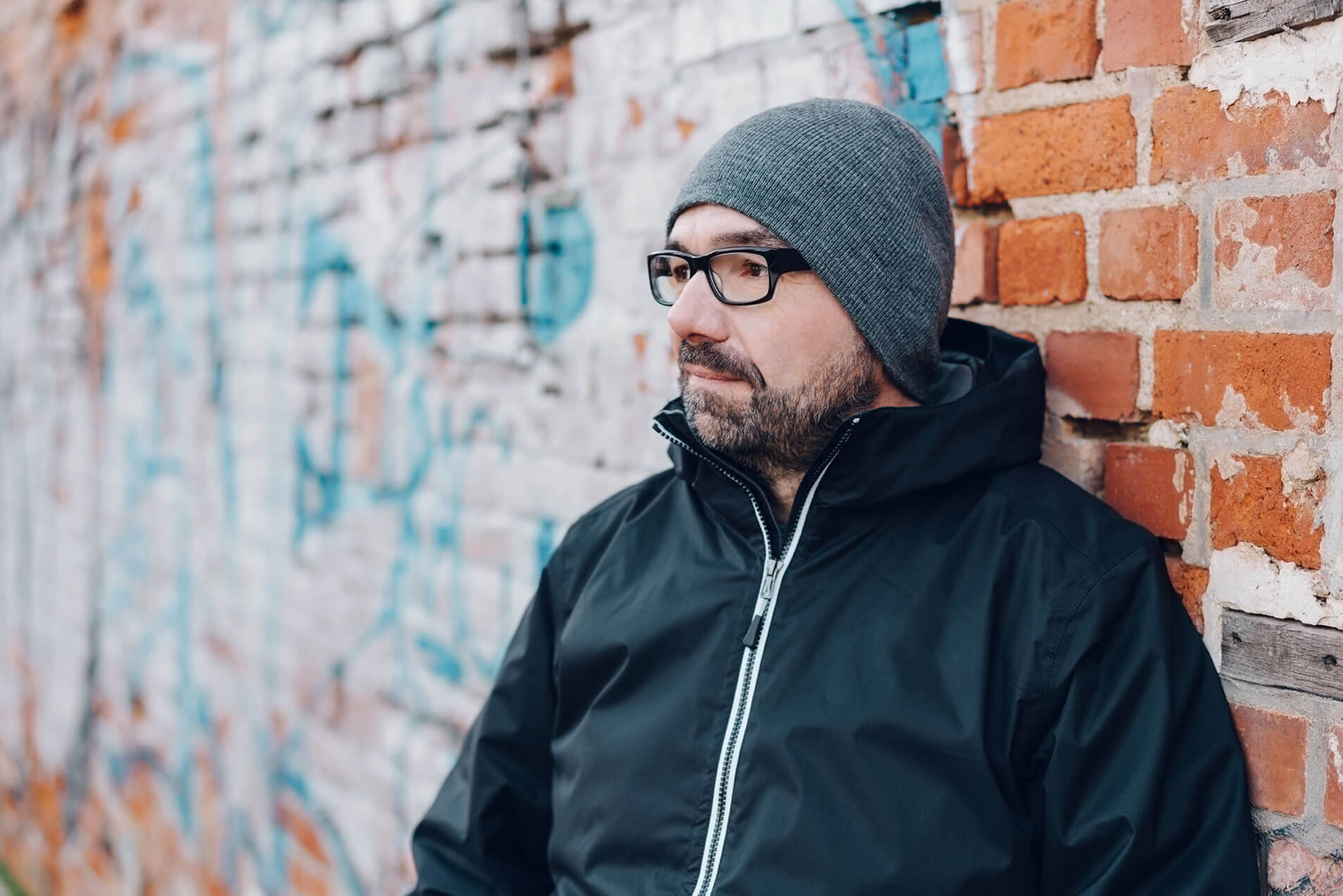 stressed man thinking leaning against a brick wall